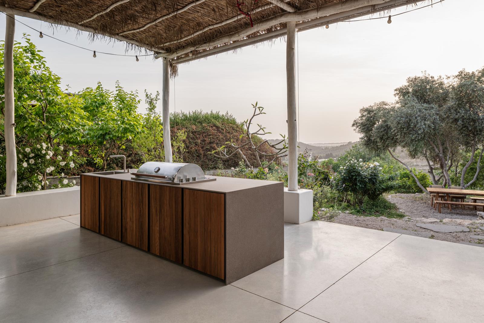 STRATO timber-slat island under a thatch pergola with valley view