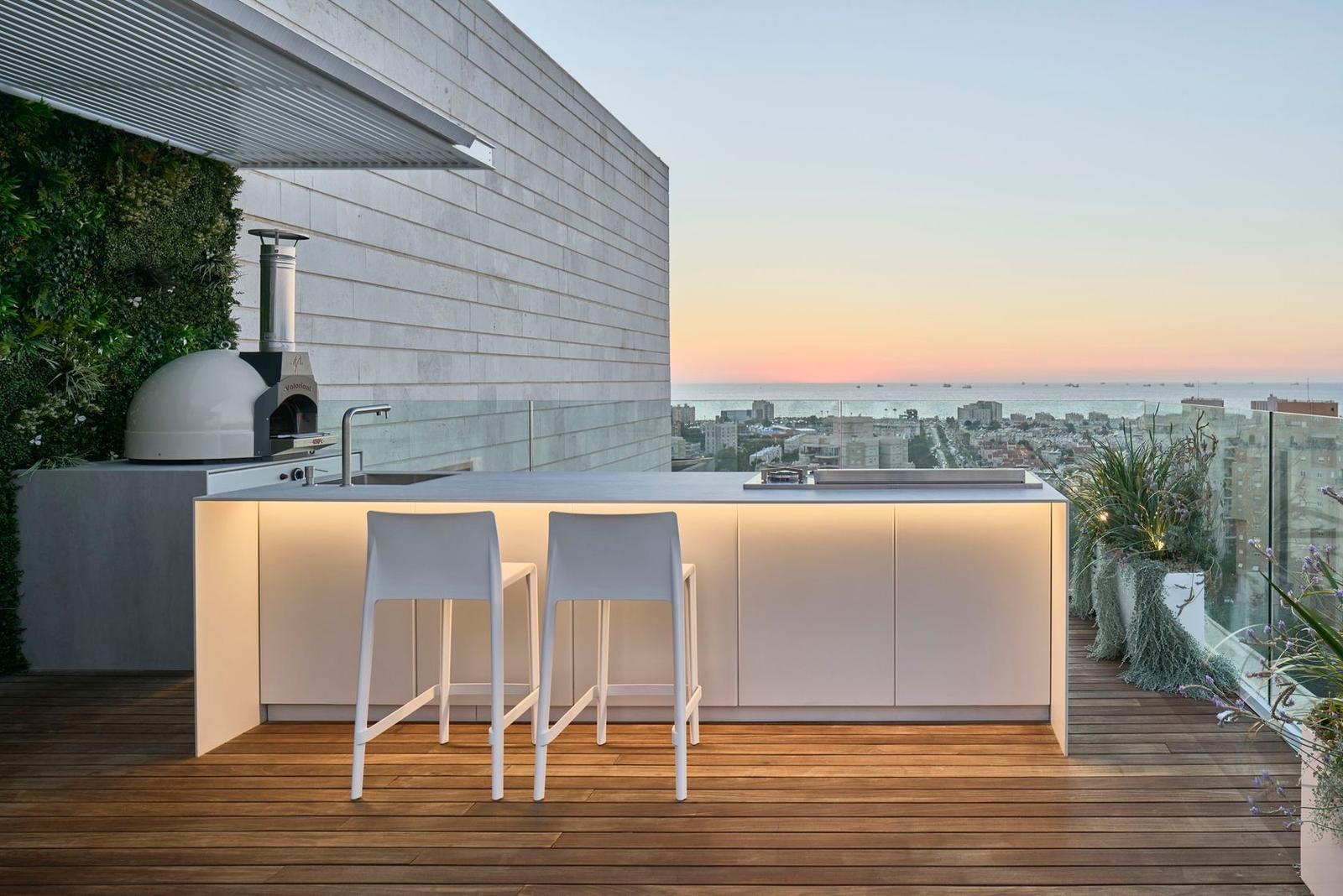 UNICA 300 outdoor kitchen island with bar seating on a rooftop terrace at sunset