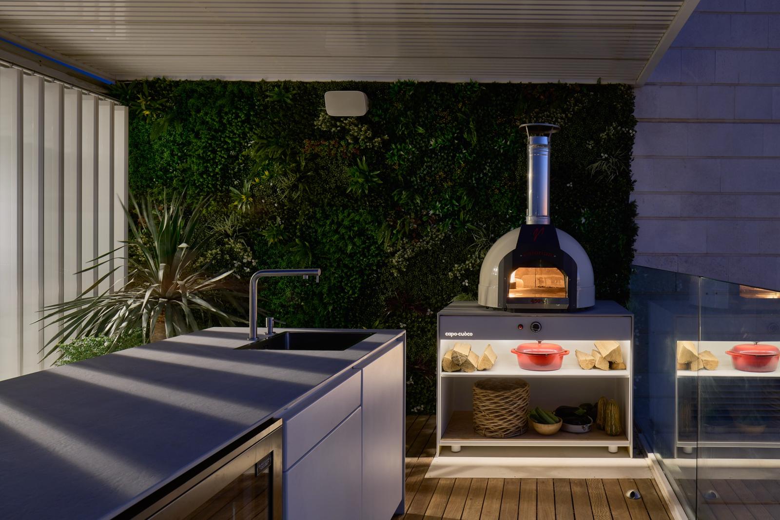 Dark UNICA counter with oven against a green wall at night