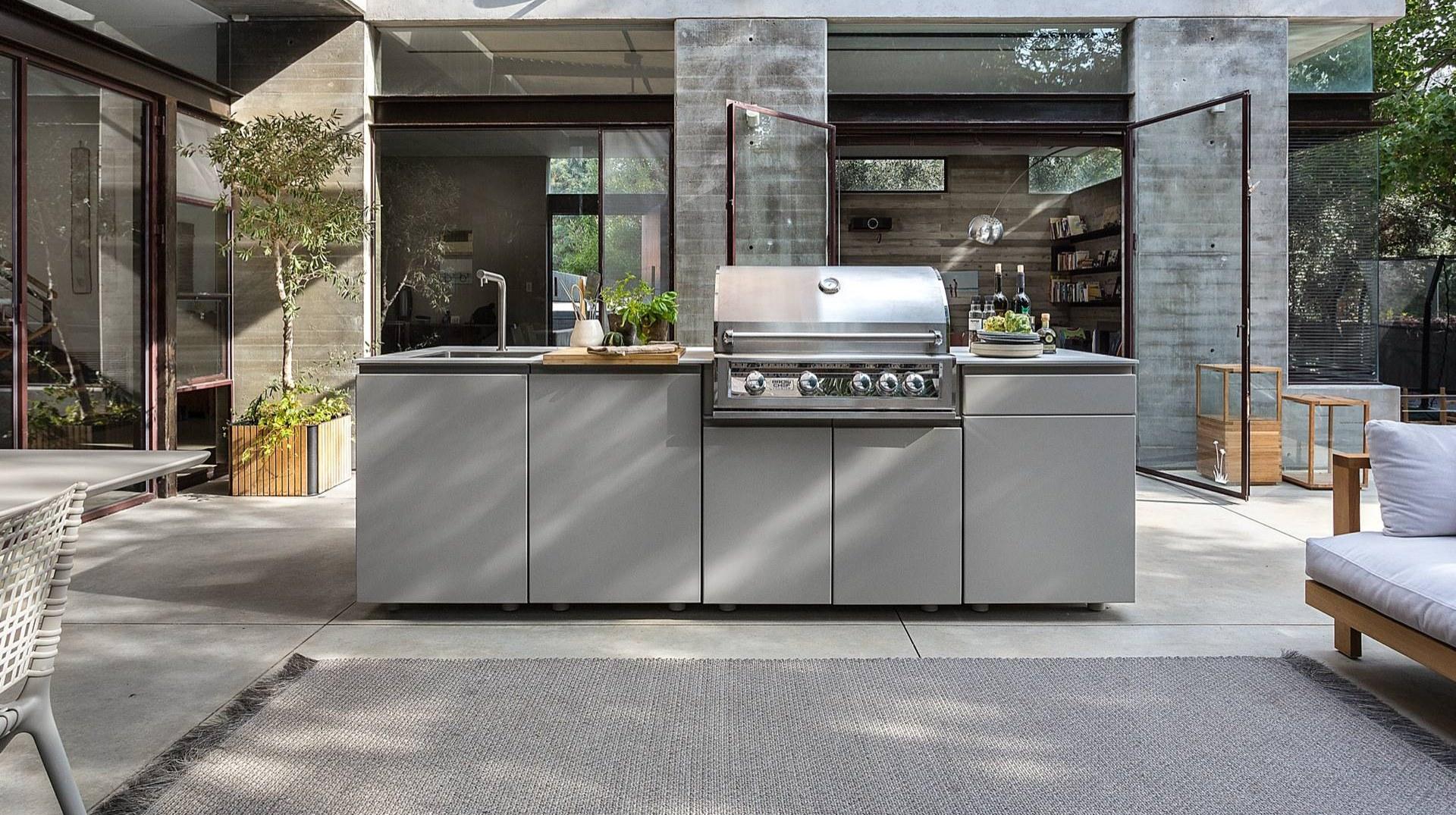 Outdoor kitchen with built-in stainless grill in a sheltered courtyard, cooking through all four seasons